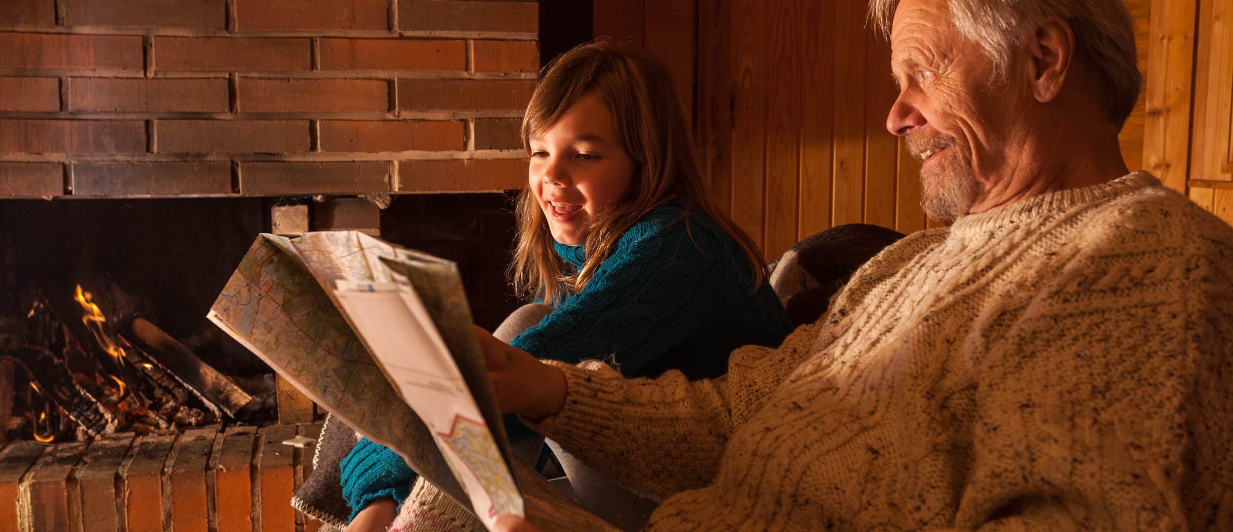 Takan ääressä vanhepi mieshenkilö ja ruskeahiuksinen tyttö lukemassa lehteä.