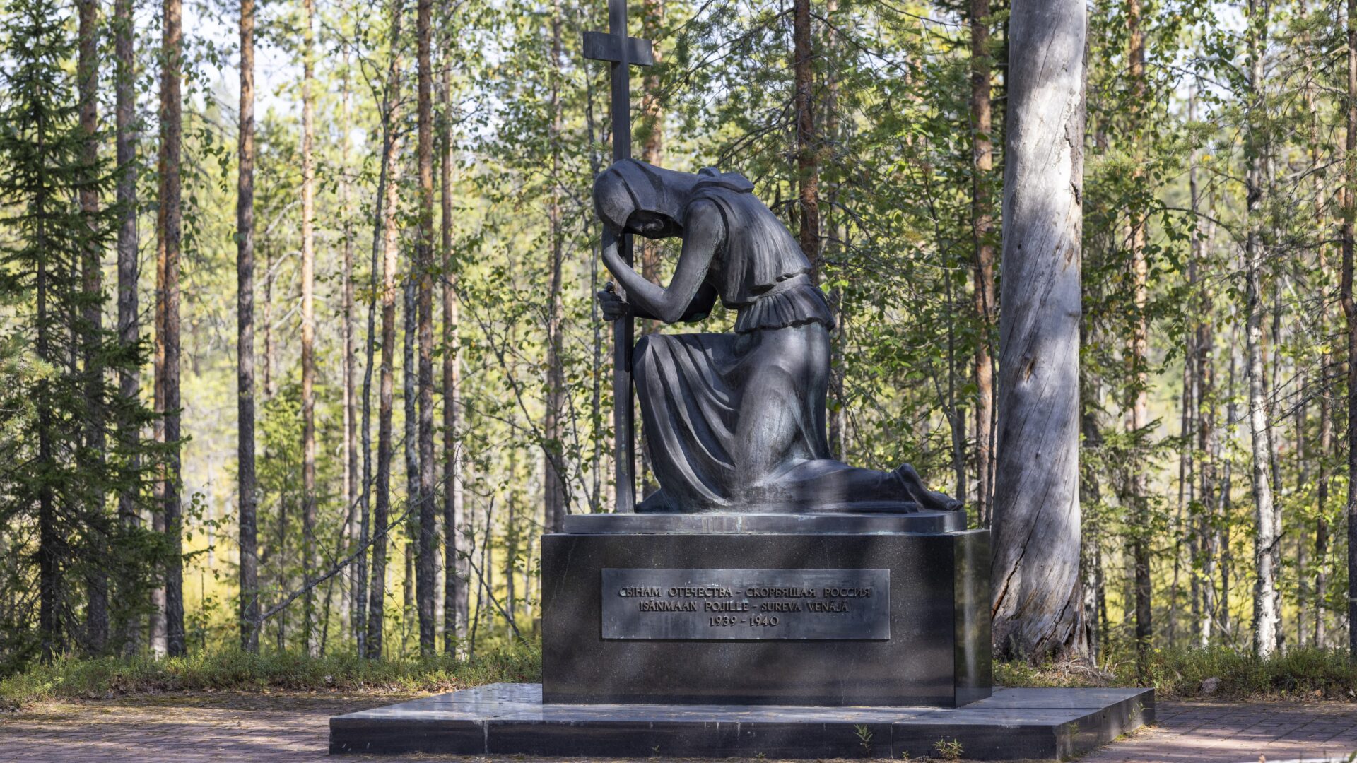 Venäläinen muistomerkki. Muistomerkissä sotilas polvillaan nojaamassa ristiin. Muistomerkki on pronssista valettu patsas.