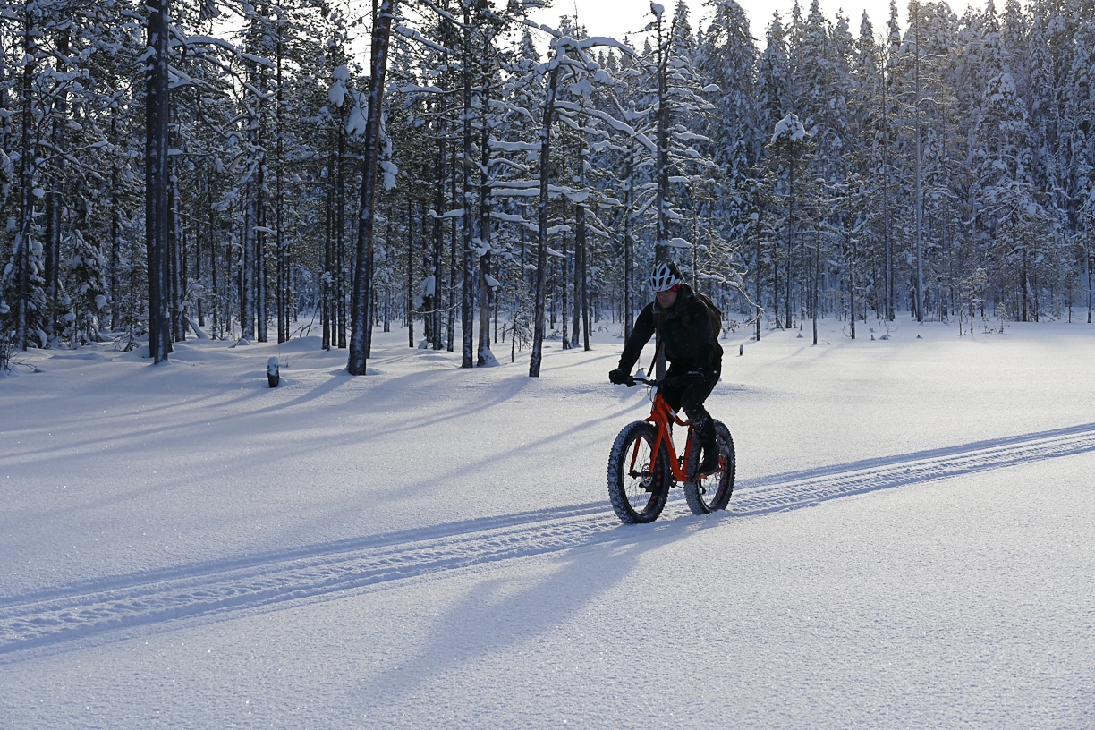 Henkilö ajaa läskipyörällä talvimaisemassa.