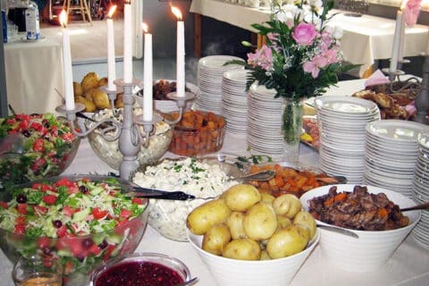Juhlapöytä, jossa tarjolla perunaa, salaatteja, lihaa ja juureksia.
