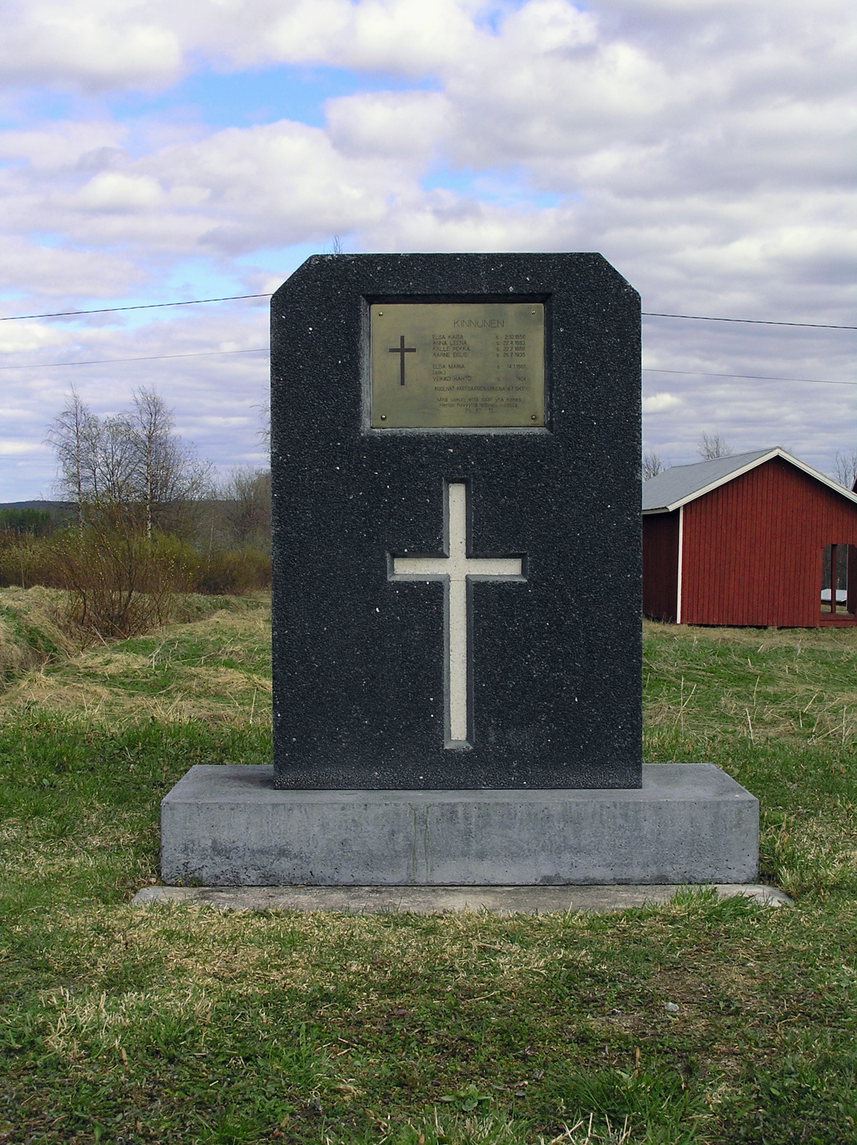 Muistomerkki, jossa ristin kuva ja laattaa, jossa lueteltu partisaani-iskussa menehtyneiden nimet.