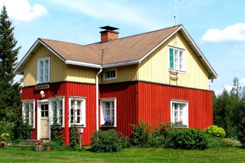 Arolan maatilan kelta-punainen päärakennus kesällä.