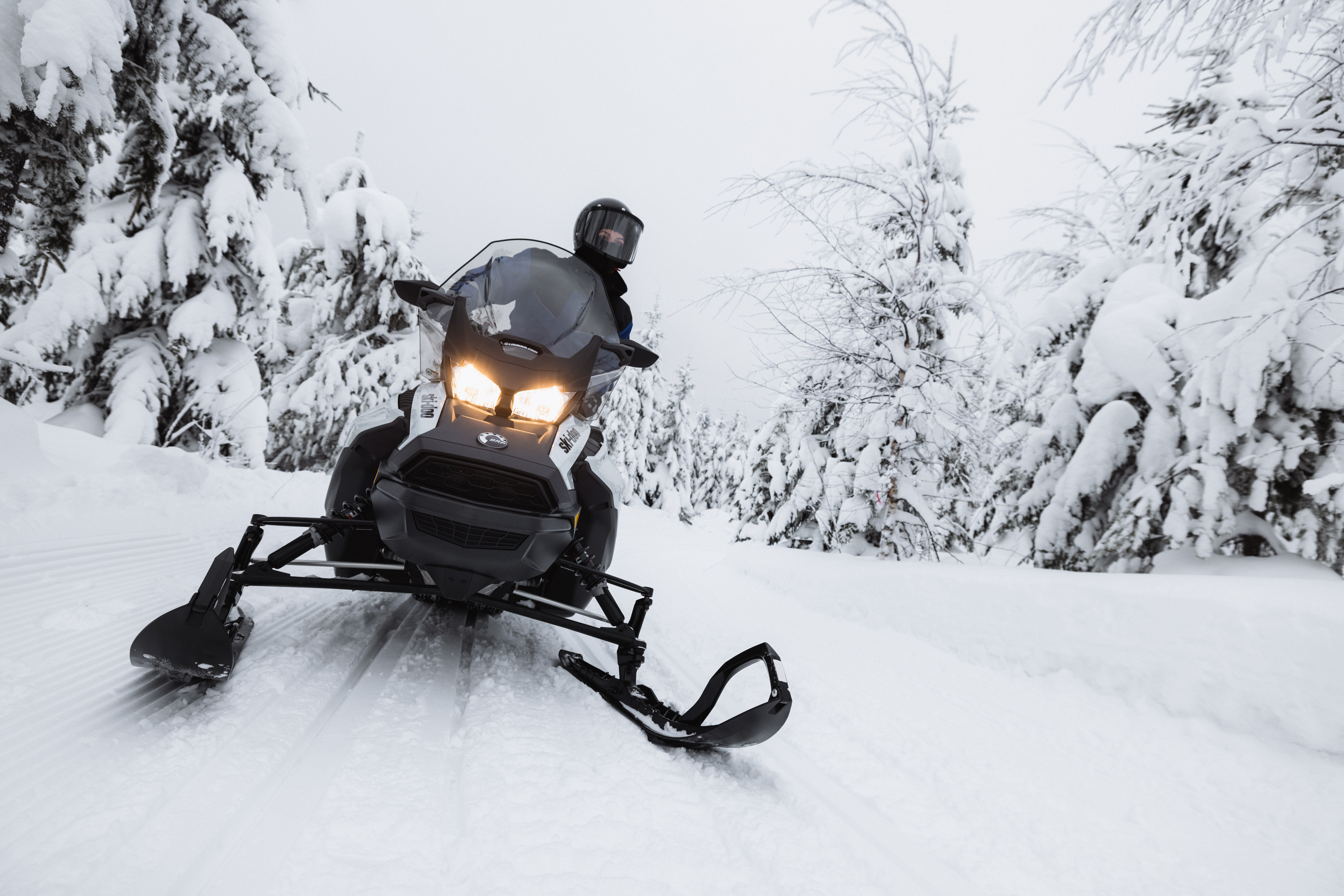 Moottorikelkkailija lumisessa maisemassa uralla.