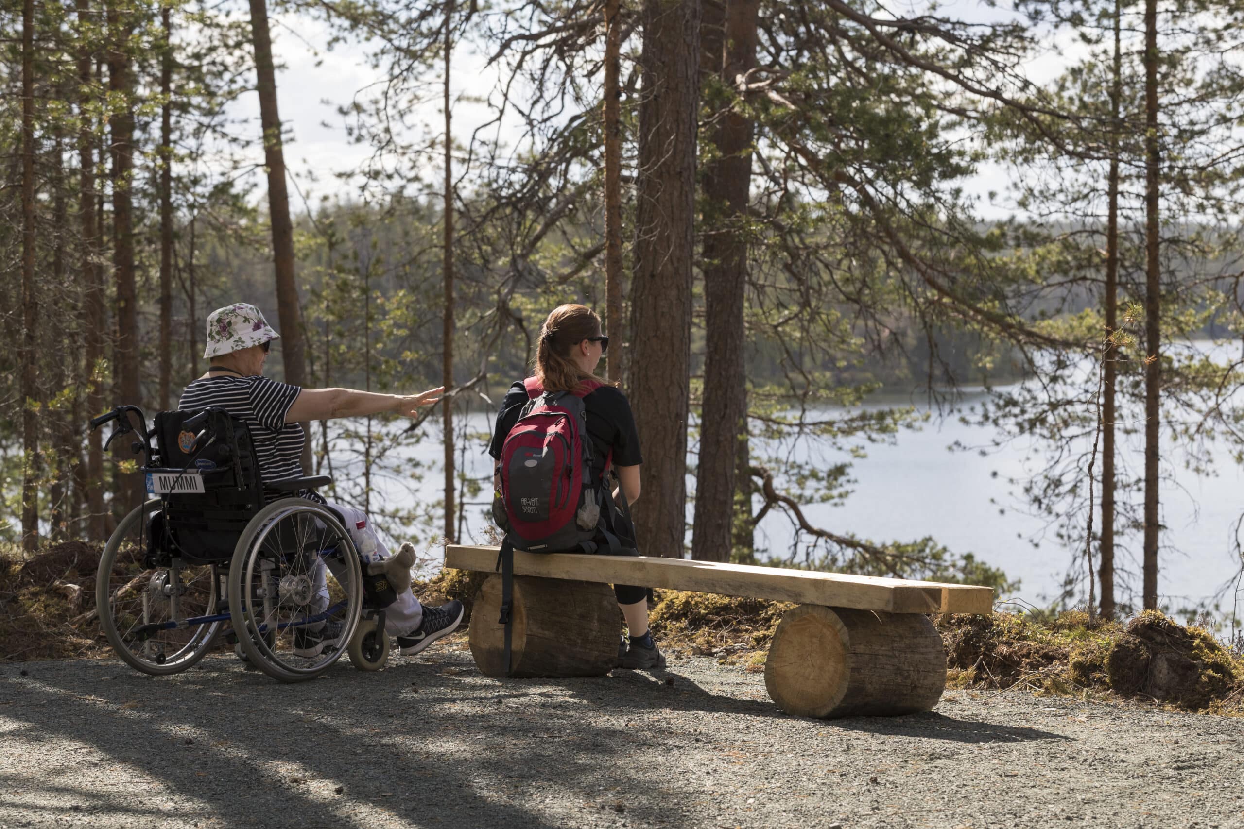Esteetön reitti, jonka varrella taukoa pitävät nainen pyörätuolissa ja nainen istuen puisella tuolilla.