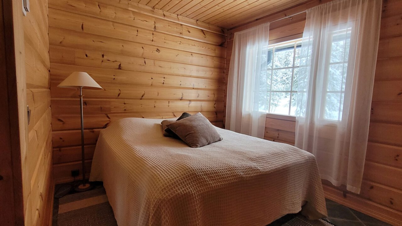 Makuuhuoneessa parisänky, jonka päällä vaalea sängynpeitto ja kaksi tyynyä.