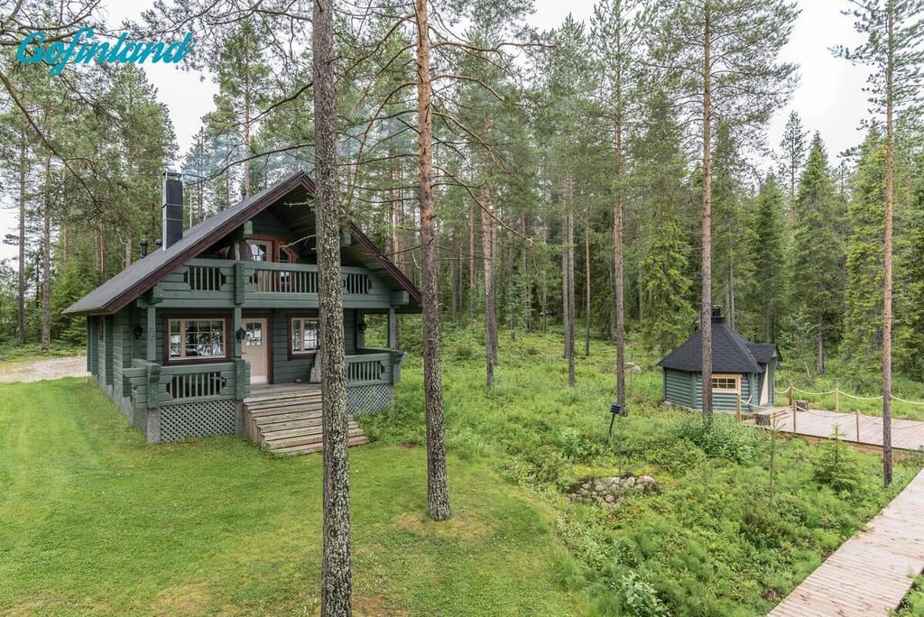Villa Lähteenkorvan ulkokuvassa vihreä kaksikerroksinen mökki ja grillikota.