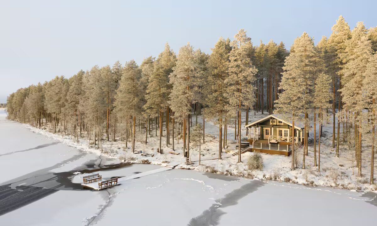 Ilmakuva mökistä, puut metsässä kuurassa ja järvi jäässä.