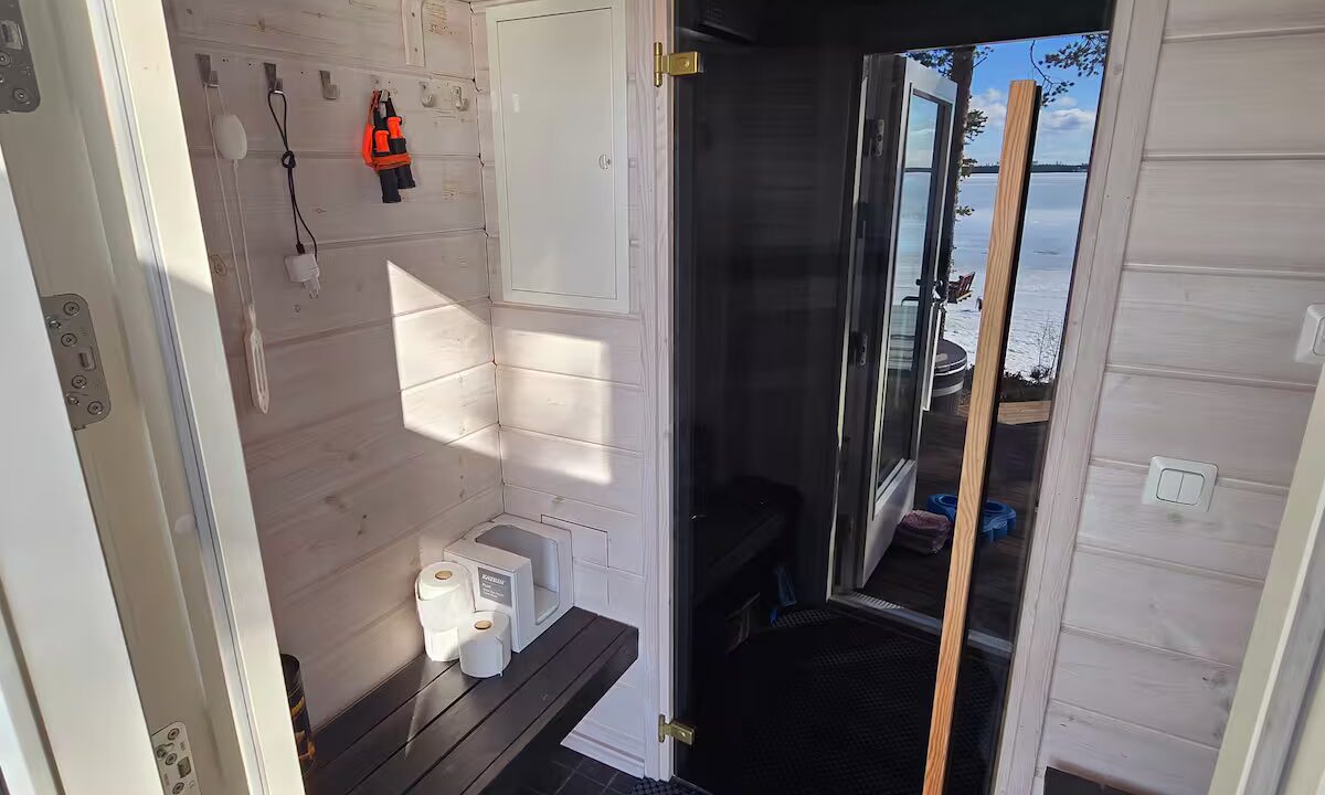 Pukuhuoneessa tummat penkit ja lasinen ovi saunaan.