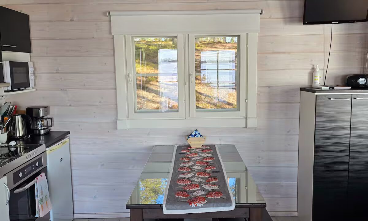 Mökin ruokailutilassa tumma ruokapöytä ja penkit sekä valkoinen ilmalämpöpumppu.