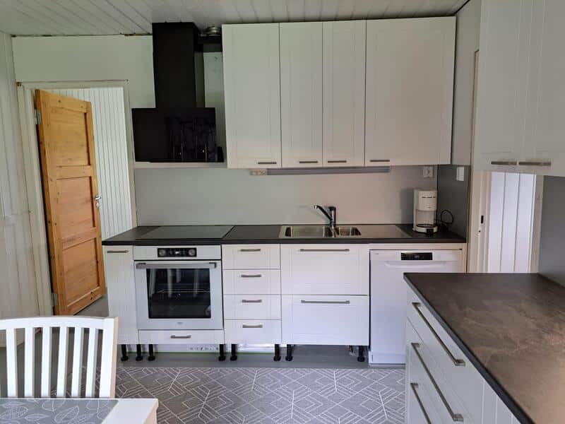 Valkoiset keittiönkaapit ja tummat pöytätasot.