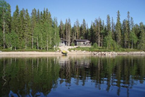 Järven rannalla, metsän ympäröivänä harmaa mökki ja saunatupa