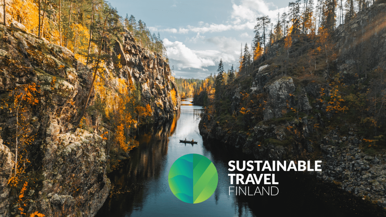 Julma-Ölkyn kanjonijärvi ruskan aikaan, melojia vedessä. Kuvan päälle lisätty Sustainable Travel Finland -logo.